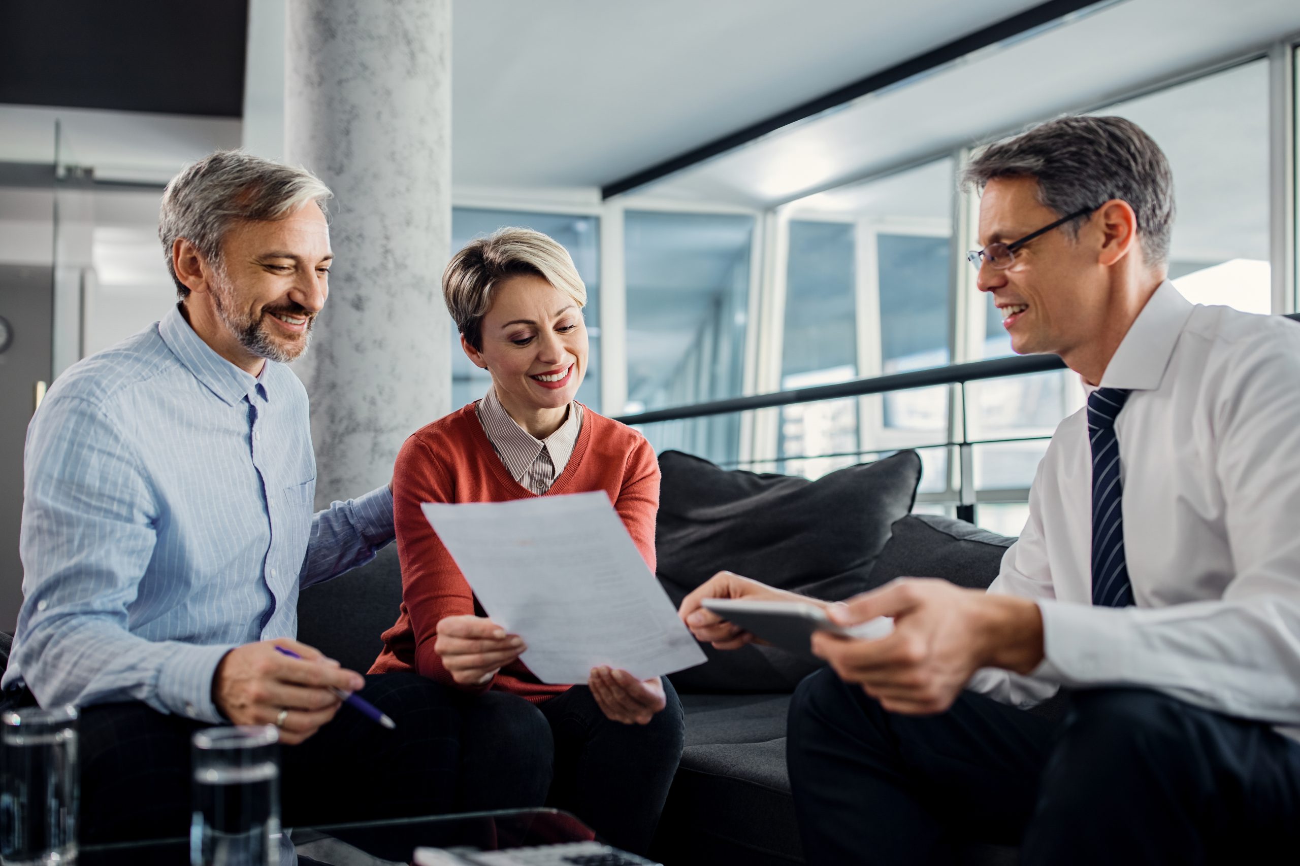 Happy couple analyzing an agreement with their insurance agent during a meeting in the office.